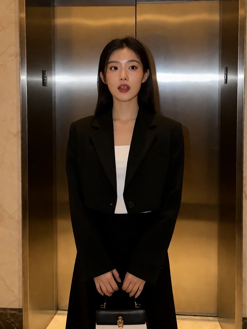 成人短视频电梯偶遇图：虚构成年女子穿黑色短西装站在明亮酒店电梯前